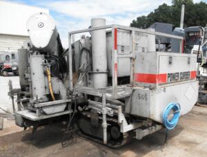 Power Curber 5700-B machine parked outside a warehouse