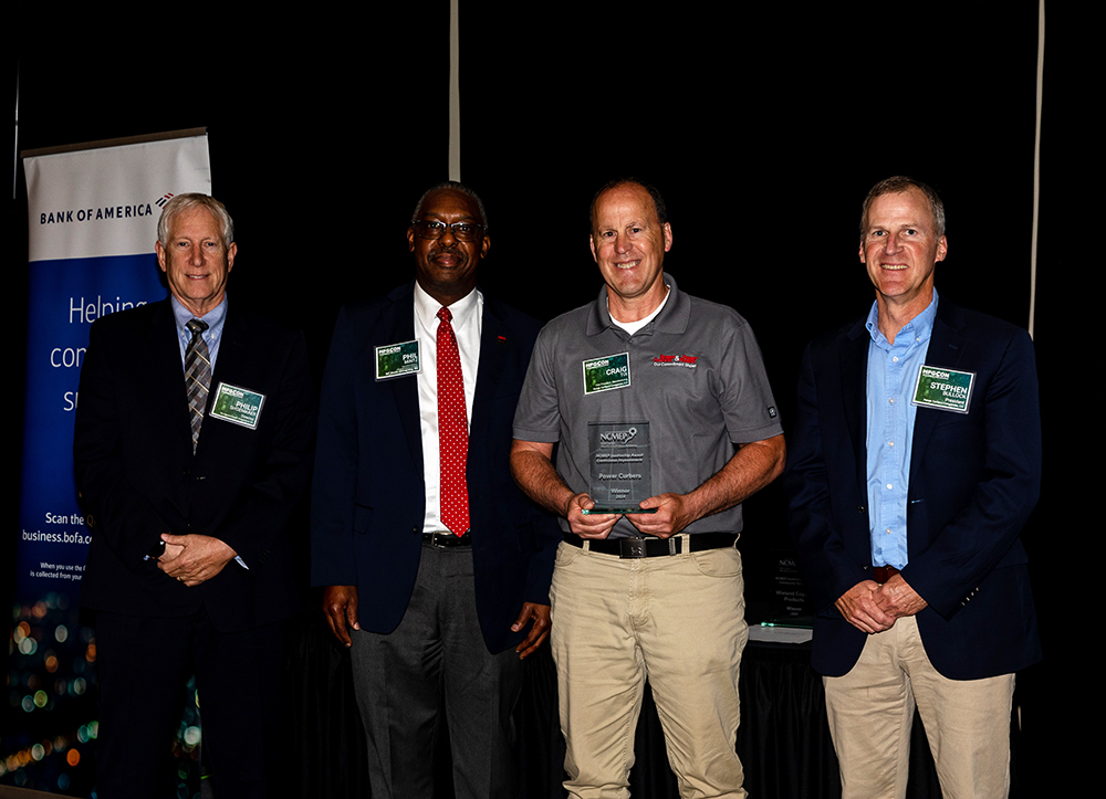 Group photo of Power Curbers leaders receiving a recognition award on stage