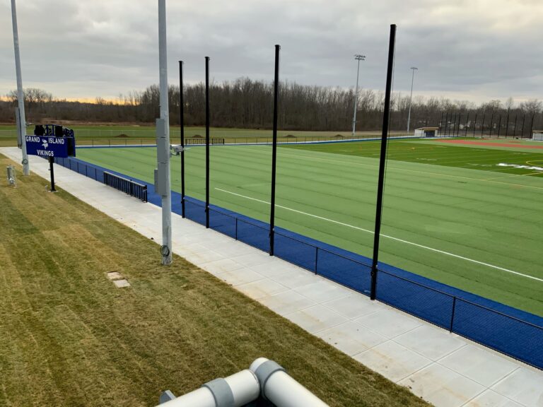 Grand Island Vikings athletic complex with turf field, curbing, and scoreboard under an overcast sky.