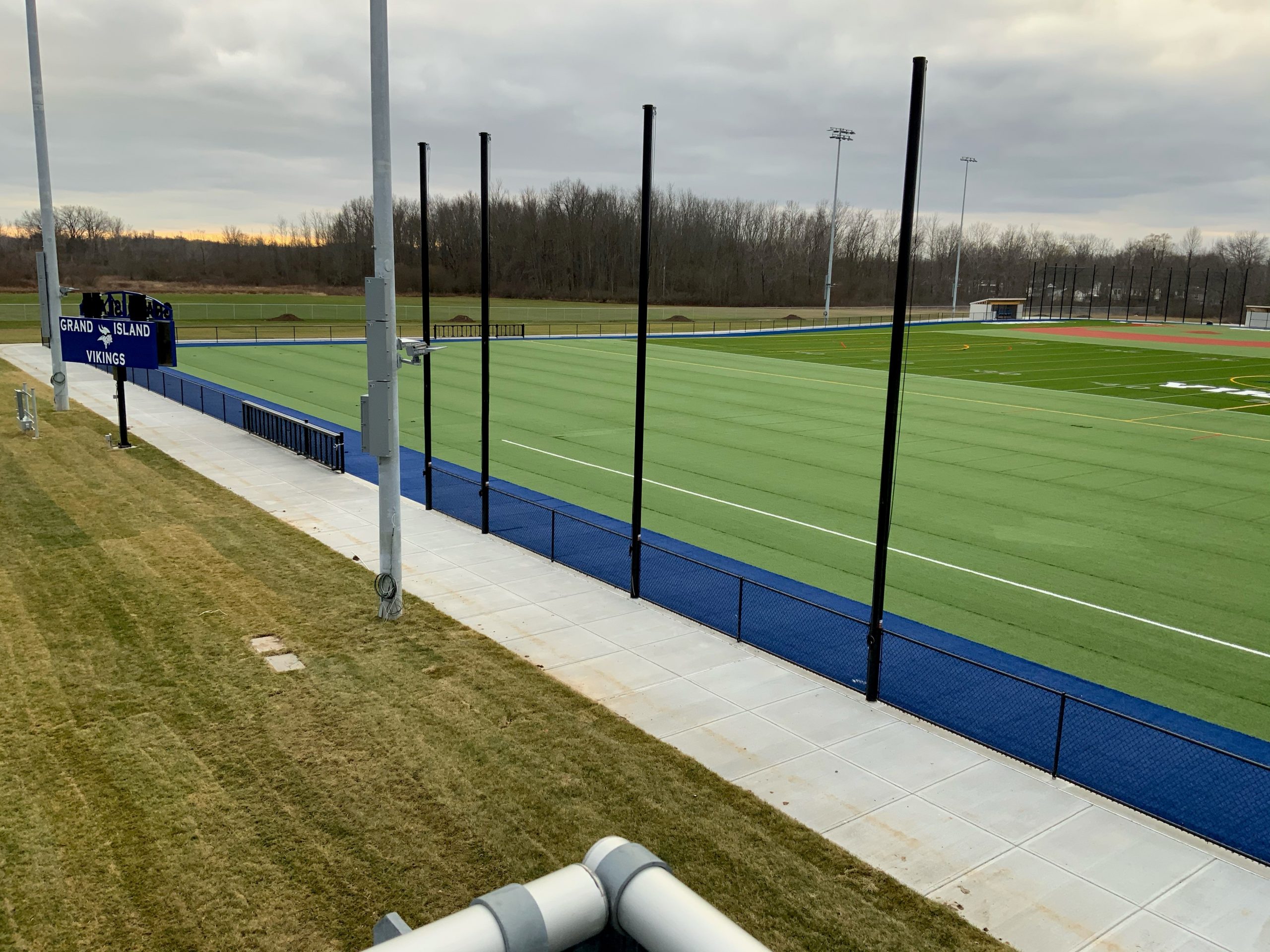 Grand Island Vikings athletic complex with turf field, curbing, and scoreboard under an overcast sky.