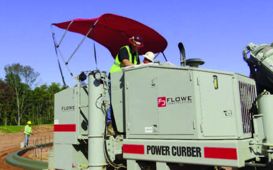 Power Curber machine branded for Flowe Construction, with two workers under a red canopy forming a concrete curb beside a mixer truck.