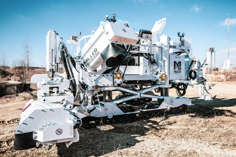 Miller Formless M-8100 machine parked on a dirt lot, showing its hopper, tracks, and mold assembly.
