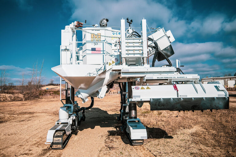 Front view of a Miller Formless M-8100 machine showing its hopper, mold, and tracks on a dirt site.