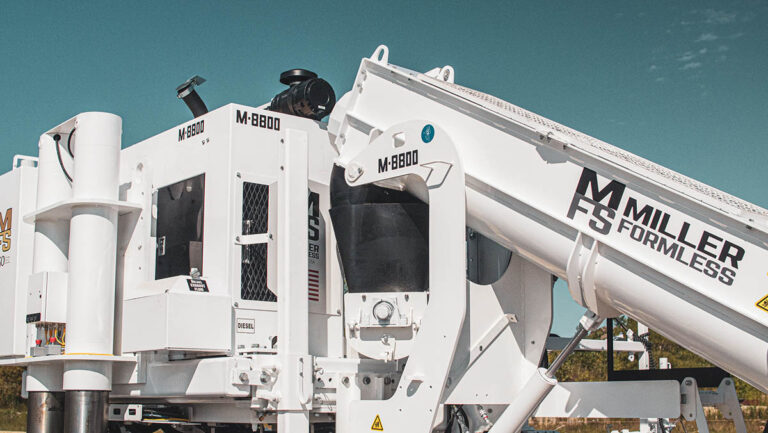 Close-up of the Miller Formless M-8800 machine's conveyor arm and cab against a teal-toned sky.