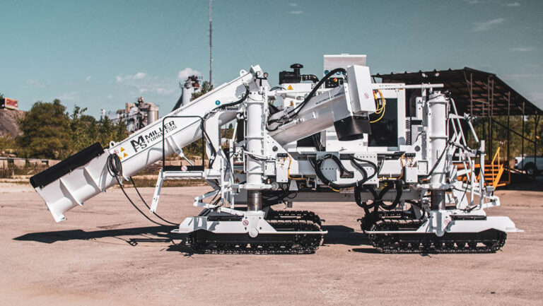 Miller Formless M-8800 machine parked on pavement near an industrial facility, showing its extended conveyor arm.