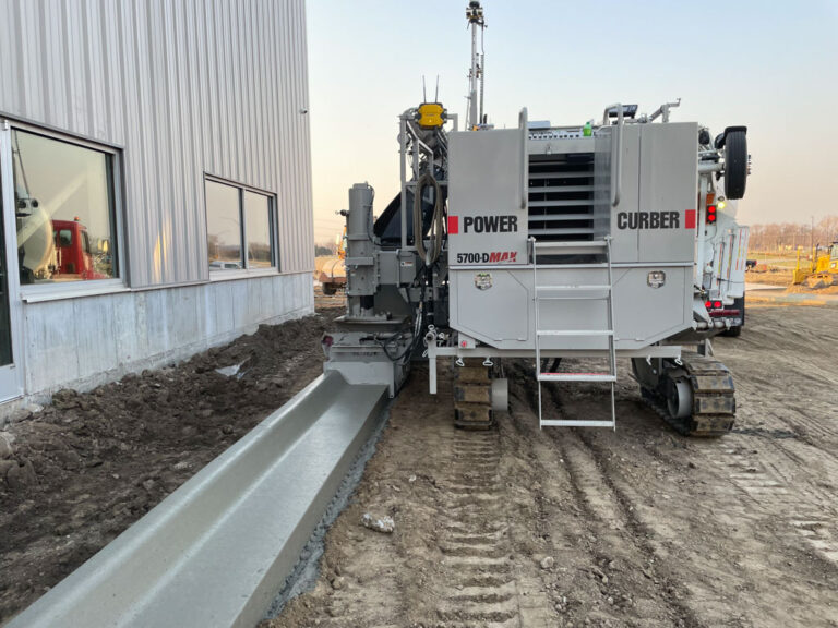 5700-D Max laying curb around a building