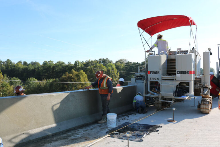 Construction team using 5700-C to lay traffic barrier