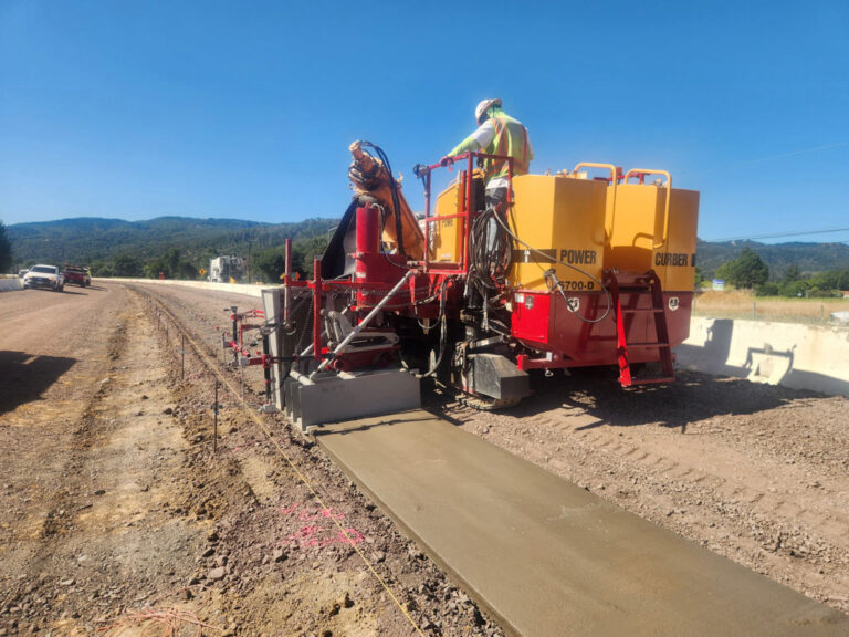 Red and yellow Power Curbers machine laying sidewalk