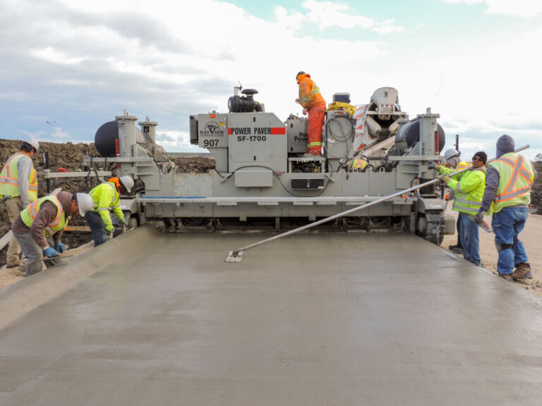Power Paver SF-1700 branded for Bay View Construction placing a wide concrete slab as several workers finish the surface with straightedges.