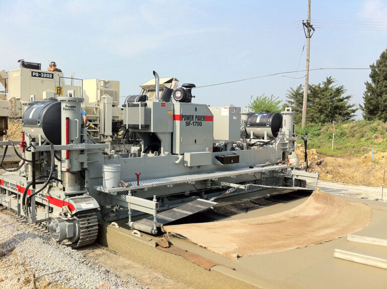 Power Paver SF-1700 machine parked beside a wide concrete slab with a burlap curing blanket partially unrolled.