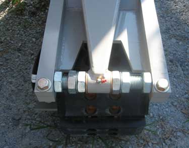 Close-up of a curbing machine's crawler alignment bracket and track roller assembly.